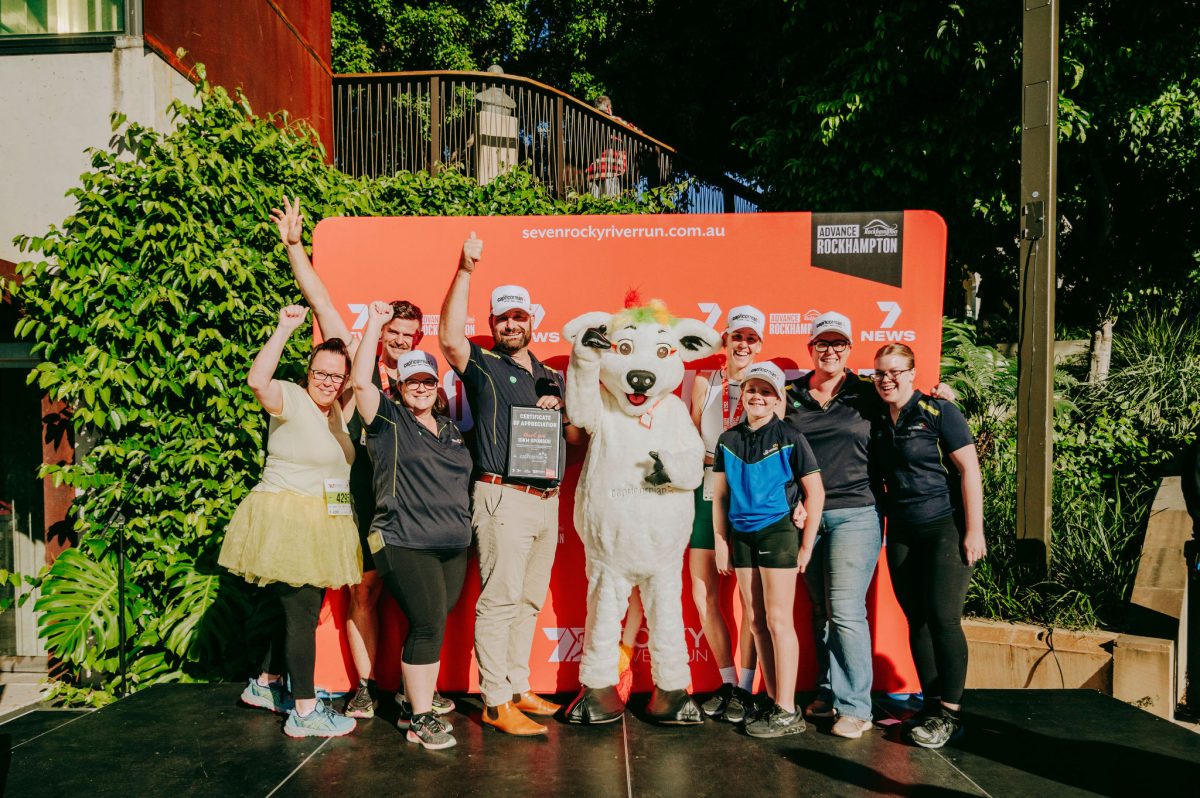 The Capricornian Bank staff cheering as they stand on the presentation stage at Rocky River Run